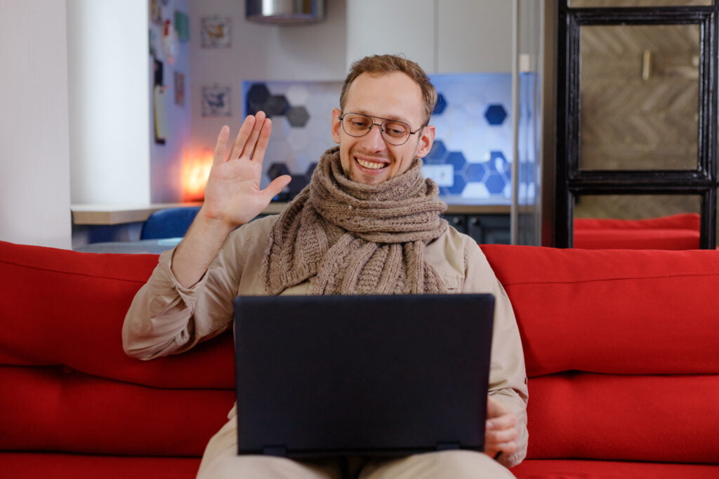 man waving at his interviewer on a video interview