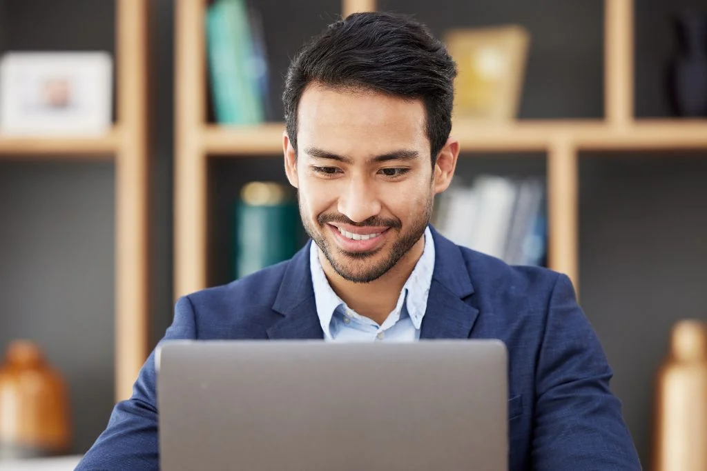 man using dynamics 365 on his laptop in front of a wall of books