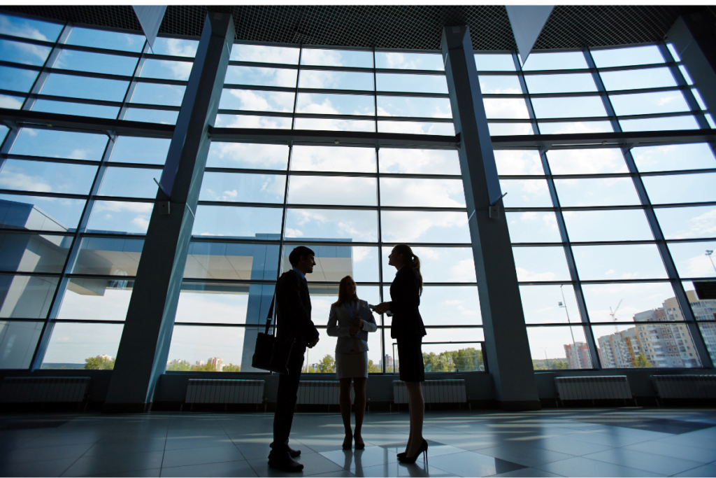 consultant talking to clients next to a large window with buildings in the near ground